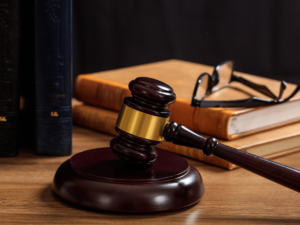 A judges gavel on a table with a lawbook and glasses.